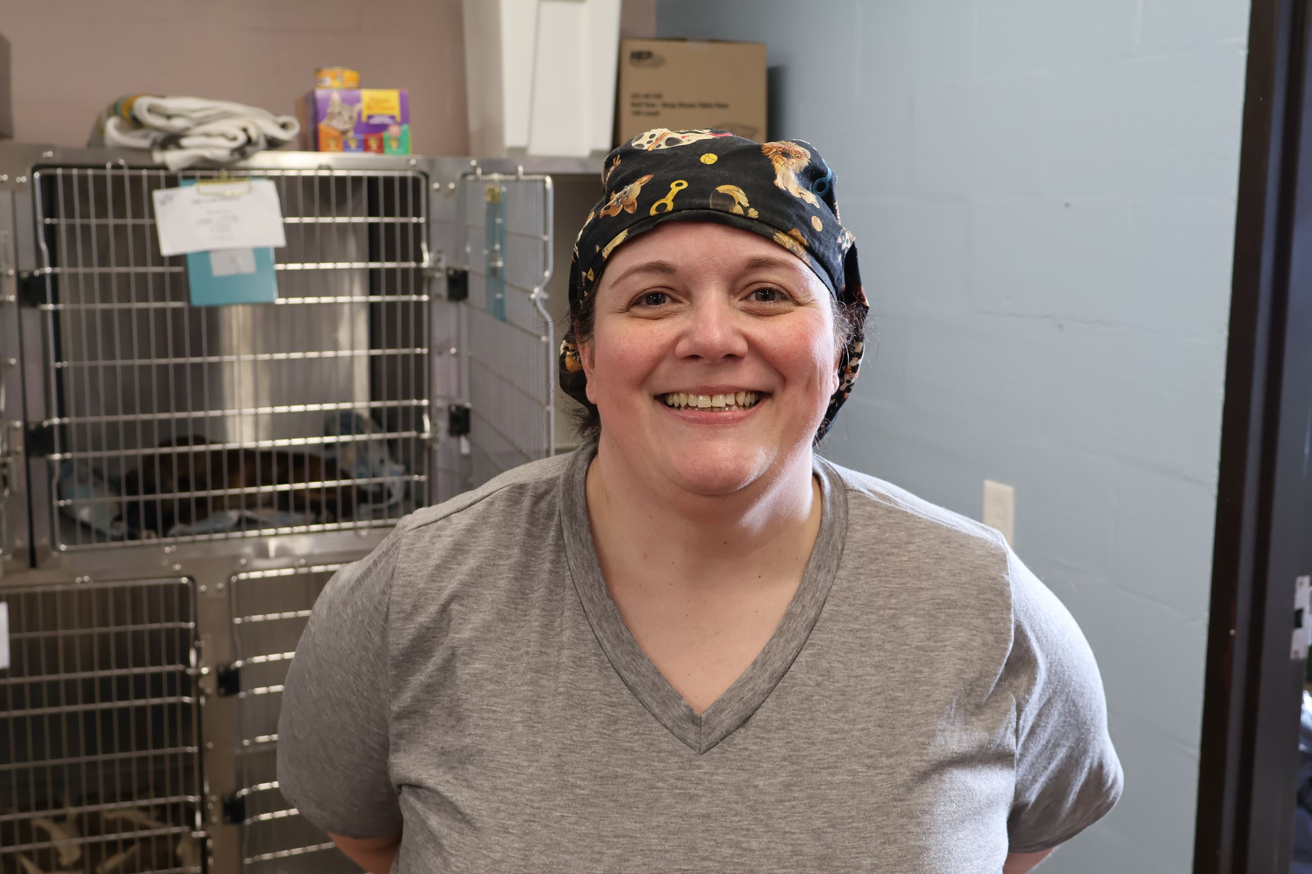 Dr. Jennifer Odum is shown standing in front of animal cages wearing medical scrubs.